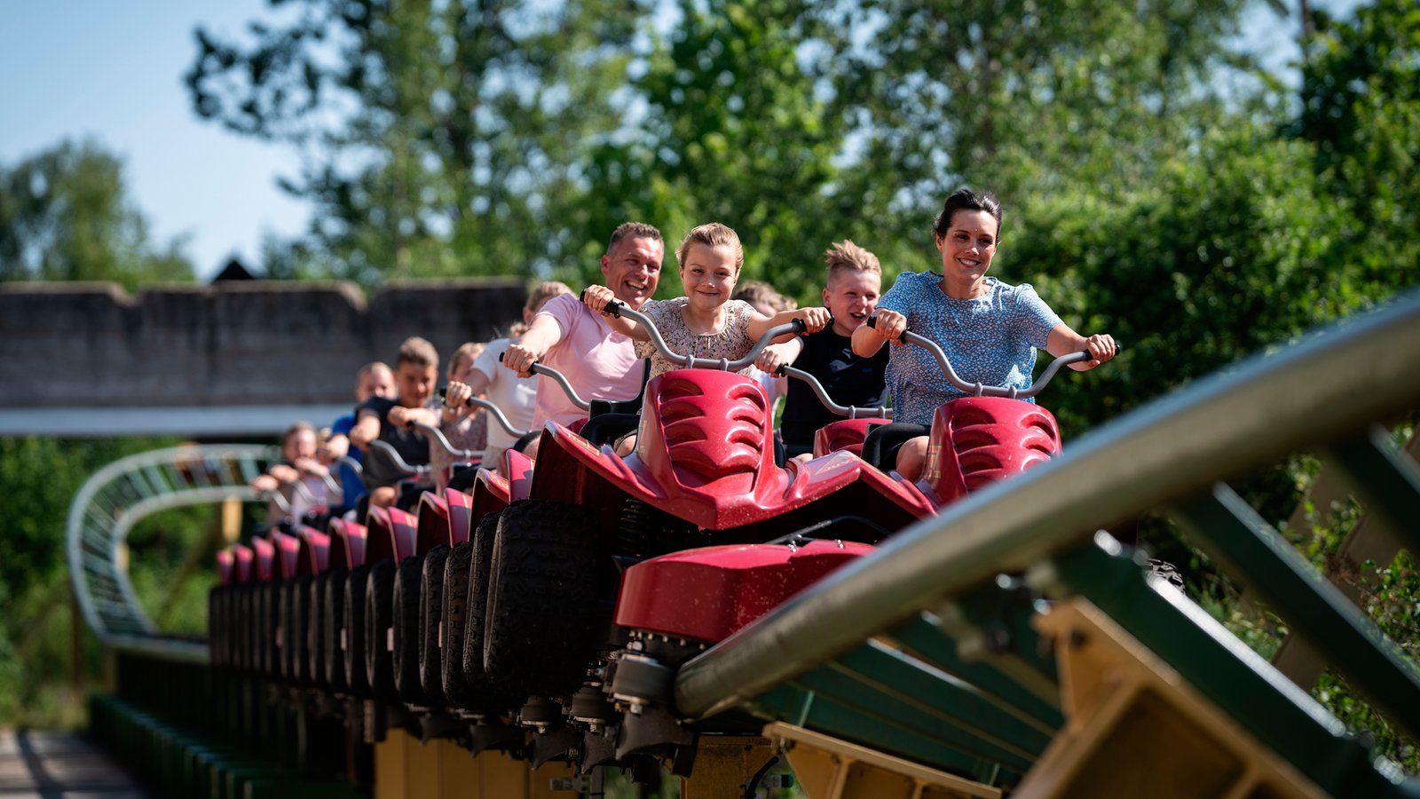 Juvelen Gjester i røde vogner på berg-og-dal-banen Juvelen i Djurs Sommerland.
