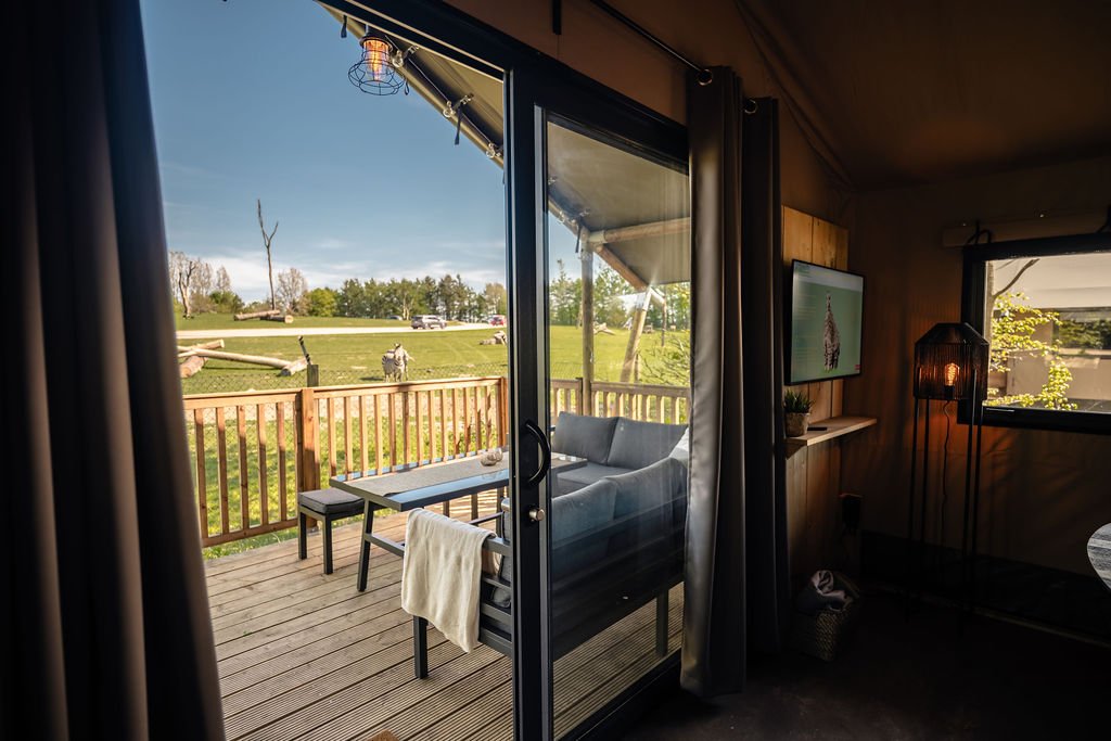 Inne i safariteltet Innsiden av et safaritelt i Safari Camp ved Givskud Zoo, med sofa, spisebord og utgang til terrassen.